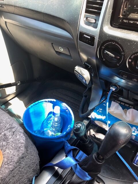 "Compact car storage bin in a vehicle hanging off a gear stick to keep vehicle neat and tidy"