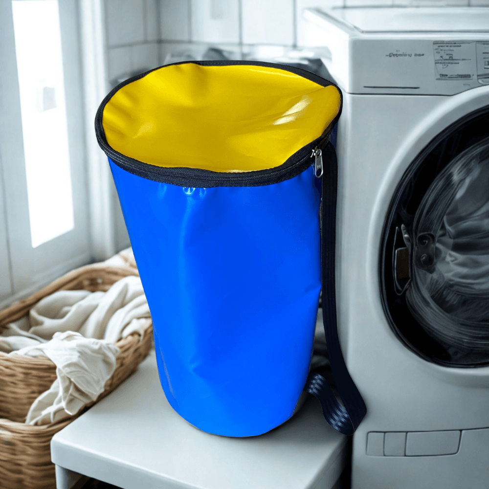 Dust & Iron PVC laundry bag sitting beside a washing machine – durable water-resistant bag for clothes and laundry storage.