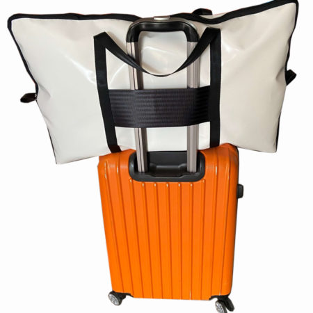 White and black PVC pillow carry bag on luggage at an airport, lightweight protective travel accessory.