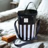 Black and white striped Shower Mate toiletry bag with shoulder strap and Dust & Iron branding displayed on a neatly made bed