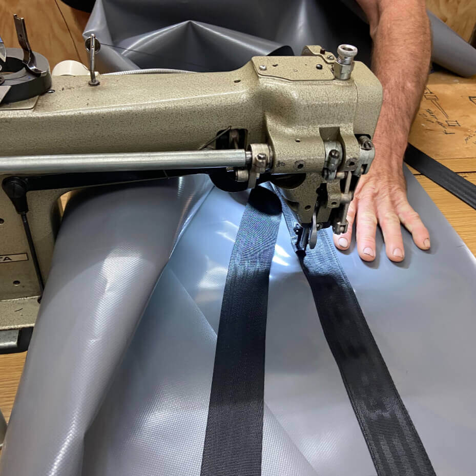 Cam sewing a heavy-duty PVC gear bag on an industrial sewing machine at the Dust & Iron workshop in Flinton, Queensland.
